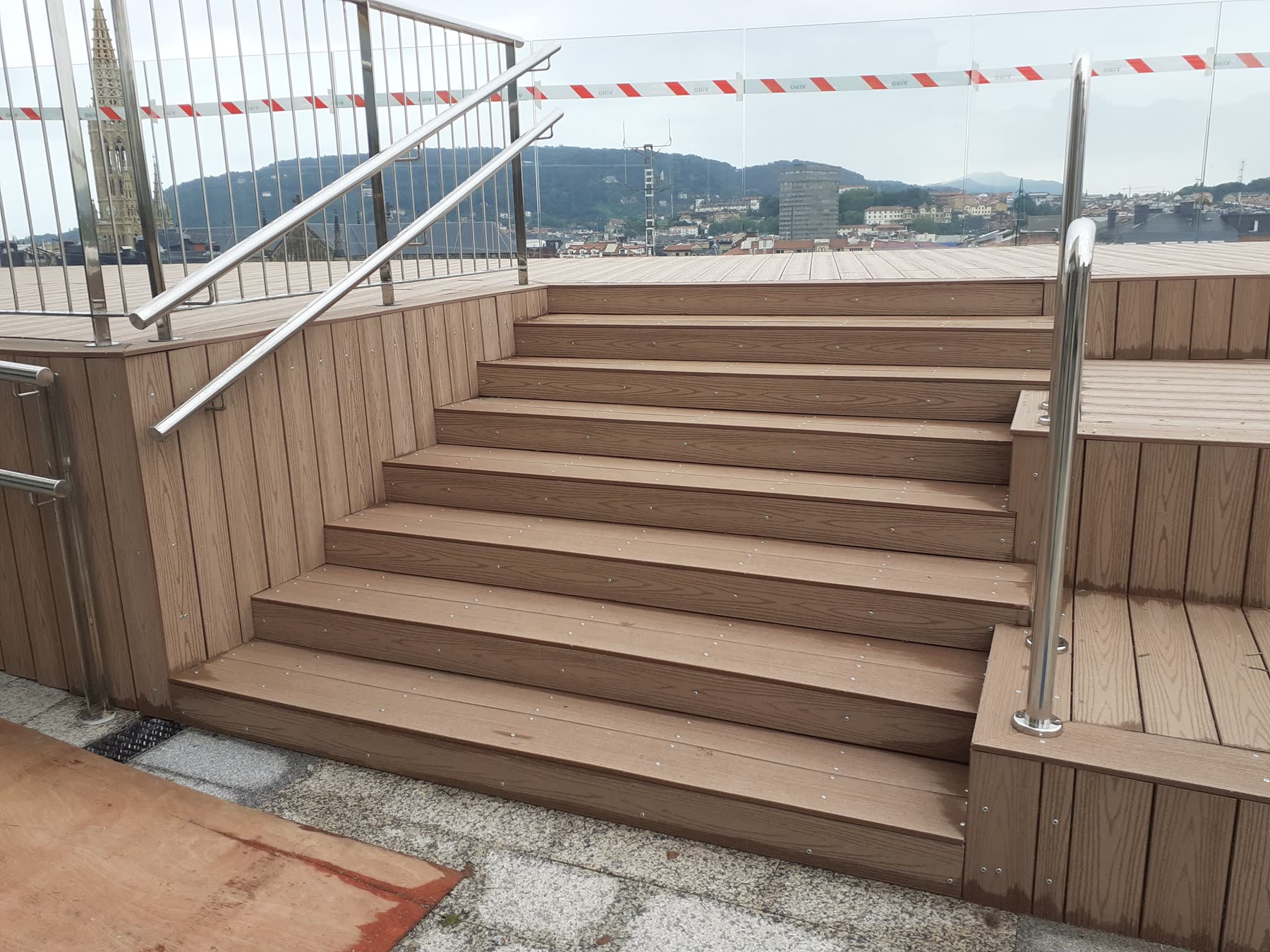 Escaleras exteriores de madera tecnológica con barandilla metálica