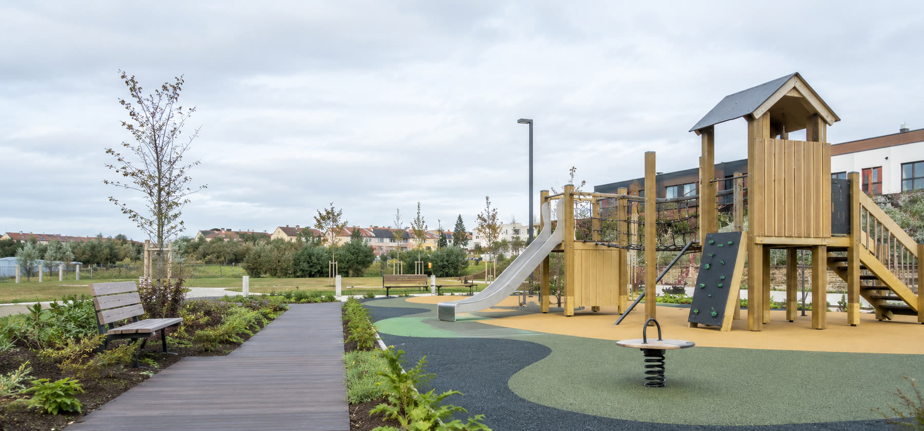 Parque infantil instalado por GARRA con pavimento continuo y entorno ajardinado